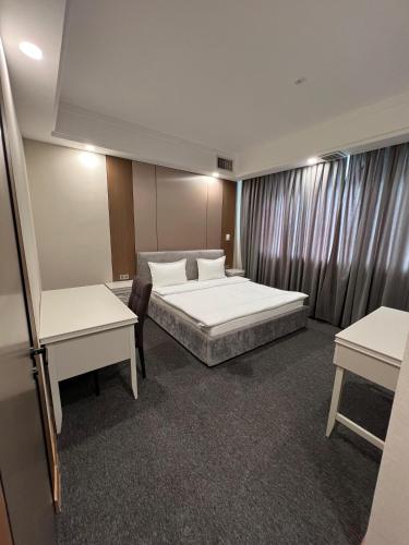 a hotel room with a bed and two tables at Mountain View Residence Hotel in Almaty