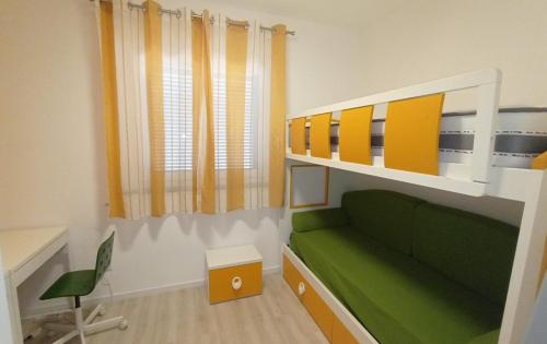 a bedroom with a green couch and a bunk bed at twins home in Castiglione della Pescaia