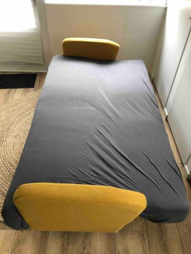 a bed in a room with a yellow and gray mattress at Private Tiny House in Bussum near Amsterdam! in Bussum