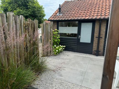 a wooden fence with a black door next to a building at Private Tiny House in Bussum near Amsterdam! in Bussum