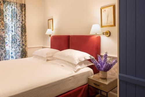 a bedroom with a bed with a red headboard and flowers at Despotiko Hotel in Mýkonos City
