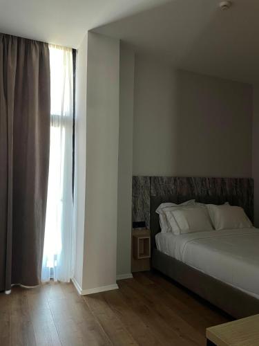 a bedroom with a bed and a large window at Tris3 Hotel in Vlorë