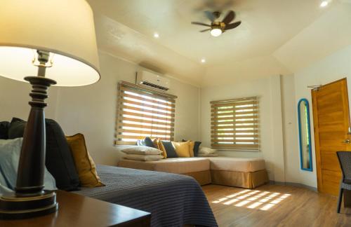 a bedroom with a bed and a couch and a ceiling fan at Stela Garden Villas in Compostela