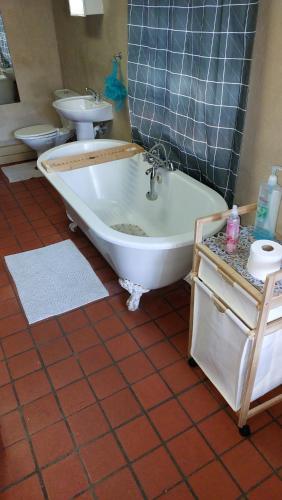 a bathroom with a tub and a toilet and a sink at Gallery Guesthouse (La Sky Villa) in Gqeberha