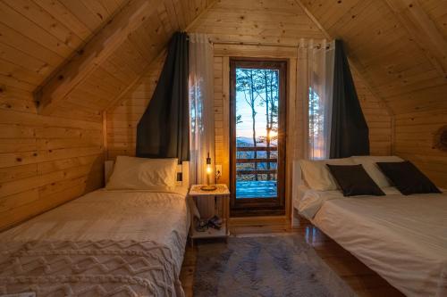 two beds in a wooden room with a window at Mountain Tree House Komovi-Radunovic 