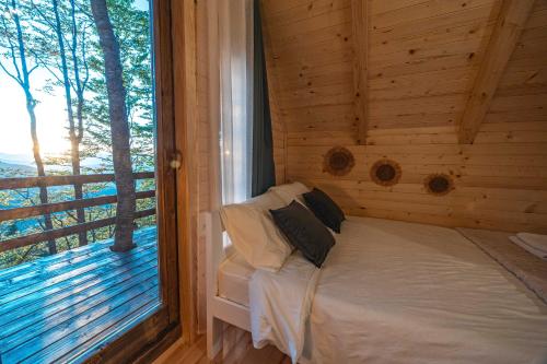 a bed in a log cabin with a large window at Mountain Tree House Komovi-Radunovic 