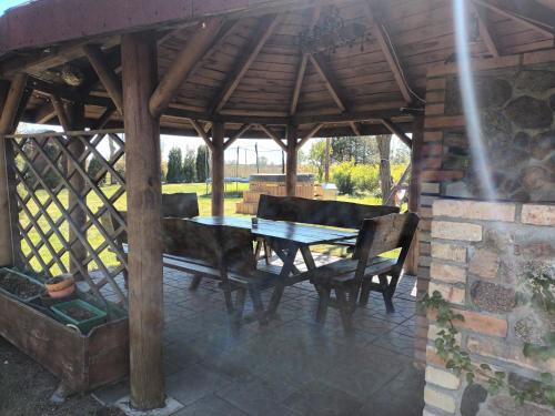a wooden gazebo with a wooden table and chairs at Bocianie Siedlisko in Janowo