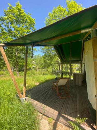 une tente verte avec une chaise sur une terrasse en bois dans l'établissement Tente Lodge en pleine nature, à Cros