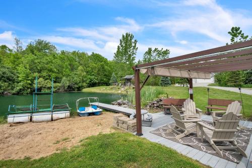 a patio with chairs and a boat on a lake at Lakeside Retreat with Hot Tub & Game Room home in Elkhart