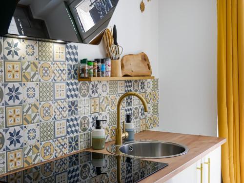 - une cuisine avec un évier et du carrelage sur le mur dans l'établissement Immeuble complet Casa Bella & Divina, à Thiers