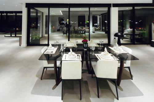 a dining room with a table and white chairs at The VVS Apartments in Accra