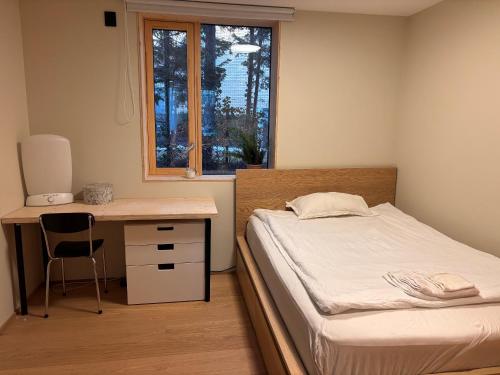 a bedroom with a bed and a desk and a window at The Wooden House, Spacious, garden, new and modern in Oslo