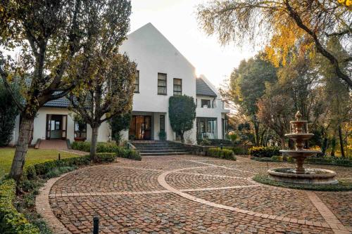 a house with a fountain in the middle of a brick driveway at Budmarsh Country Lodge in Magaliesburg