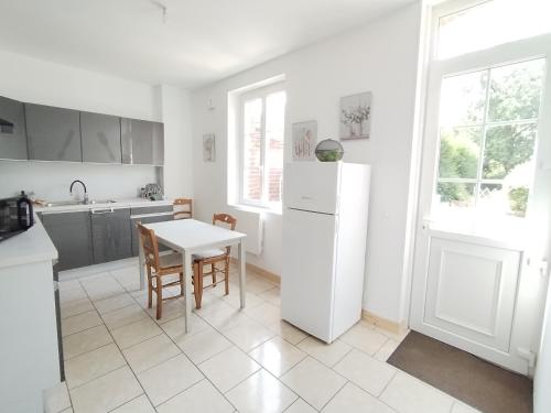 a kitchen with a table and a white refrigerator at Le Nid Douillet à 1h de Paris-Gare à 5 min à pied, logement entier in Saint-Just-en-Chaussée
