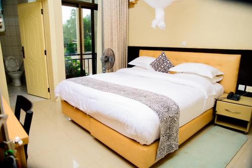 a bedroom with a large bed with white sheets and pillows at QUALITY INN HOTEL Kigali in Kigali