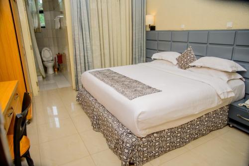 a large bed in a room with a bathroom at QUALITY INN HOTEL Kigali in Kigali