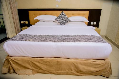 a large bed with white sheets and pillows at QUALITY INN HOTEL Kigali in Kigali