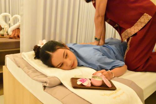 a woman laying on a hospital bed with a tray of food at Neenlawat Riverside in Surat Thani