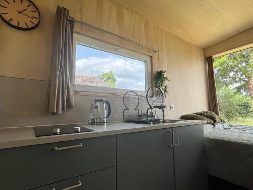 une cuisine avec un évier et une horloge murale dans l'établissement Tiny House, à Corps-Nuds