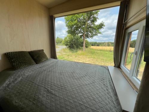 une chambre avec un lit et une grande fenêtre dans l'établissement Tiny House, à Corps-Nuds