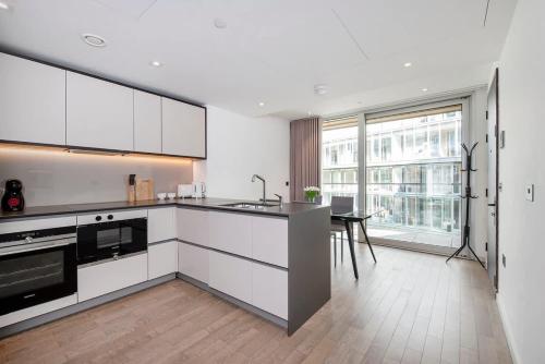 a kitchen with white cabinets and a table in it at Modern 2 Bed Battersea Power Station in London