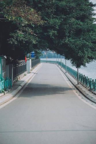 a tree lined road with a fence and trees at Luxury Pentstudio Westlake - Tay Ho, Ha Noi in Hanoi