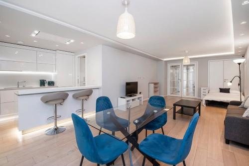 a living room with a glass table and blue chairs at Big and Bright London Bridge unit in London