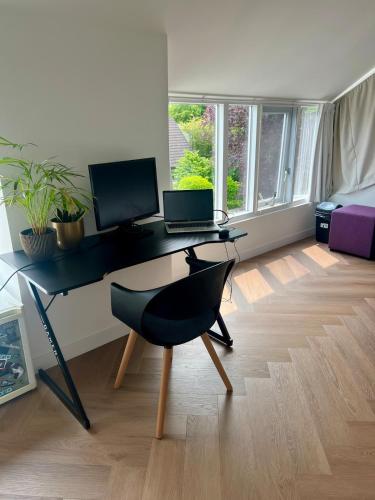 a desk with a laptop and a chair in a room at Ruime slaap kamer met werkplek en privé badkamer Leeuwarden bij Jacqueline in Leeuwarden