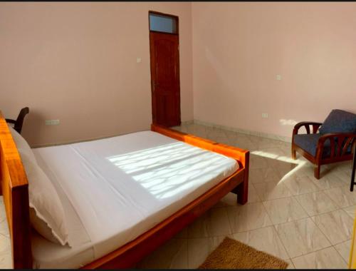 a small bed in a room with a chair at Pearl Season B&B in Gulu