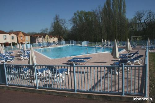 une piscine avec des chaises et des parasols ainsi qu'une clôture dans l'établissement Résidence du Lac-MONFLANQUIN Appartement RDC, à Monflanquin