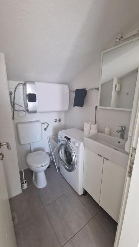 a small bathroom with a washing machine and a sink at Rooftop sea view apartment in Split