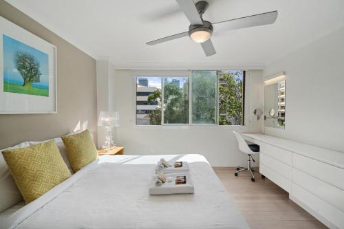 a bedroom with a bed with a ceiling fan and a desk at Inner City Harbour Views With Parking in Sydney