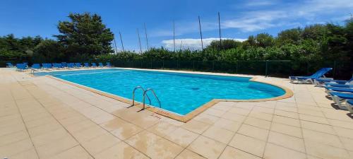 une grande piscine avec des chaises longues bleues dans l'établissement L'Aigue-Marine emplacement parfait, parking privé, à Arzon