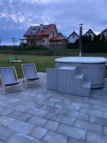 two chairs and a hot tub on a patio at Gościnny Zakątek in Chłopy