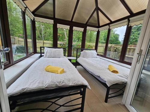 two beds in a screened in porch with windows at Carey House Long Stays Free Parking and WI-FI in Swindon