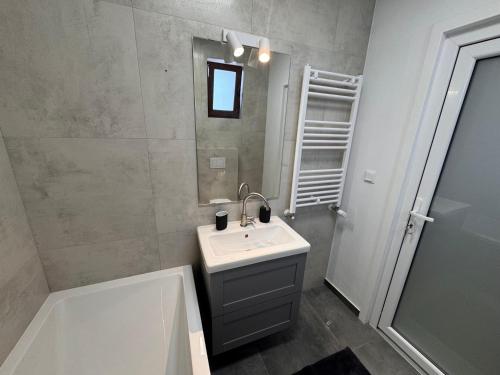 a bathroom with a sink and a mirror and a tub at AT Modern Boutique in Bucharest