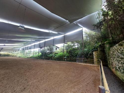 a large building with a dirt floor and a fence at Hotel Campestre Ronda Ecuestre Rionegro in La Ceja