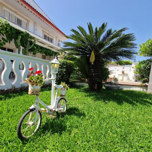 a white bike parked in the grass in front of a house at SANTA VENERE Apartments "PARCHEGGIO interno MOTO-AUTO" Ricarica auto Elettriche in Tropea