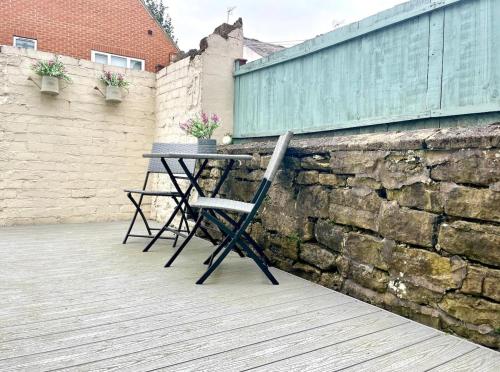 a table and a chair next to a stone wall at Wild Springs - Centraly Located House With Free Parking in Wetherby
