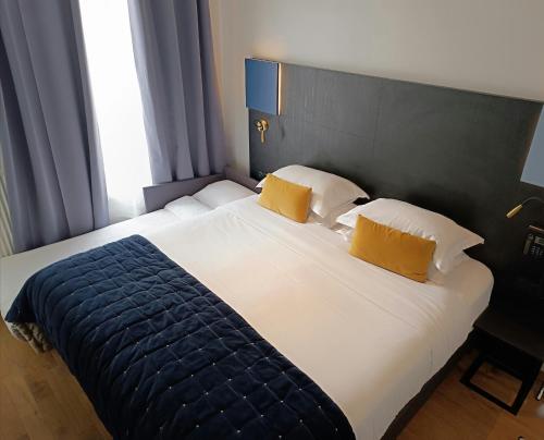 a bedroom with a large bed with two yellow pillows at Hôtel de Bellevue Paris Gare du Nord in Paris