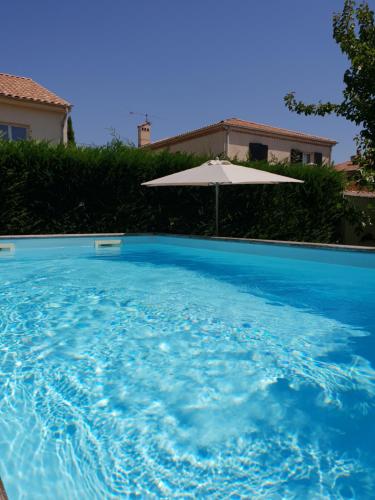 une grande piscine bleue avec un parasol dans l'établissement les lauriers roses, à Saint-Raphaël