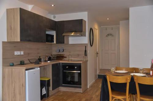 une cuisine avec des armoires en bois et une table avec des chaises dans l'établissement Le Spot Central - Calme - Cosy, à Mâcon