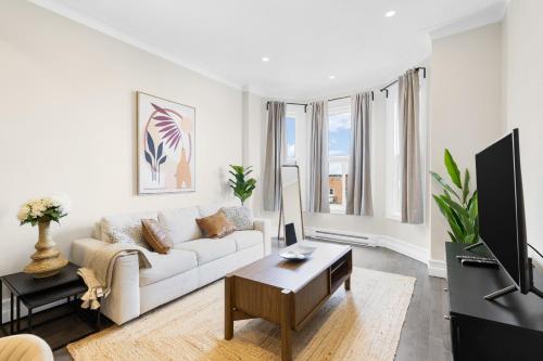 a living room with a white couch and a tv at The Parc Mile End ApartHotel in Montréal