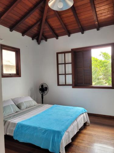 a bedroom with a bed with blue sheets and windows at CasaLegal in Búzios