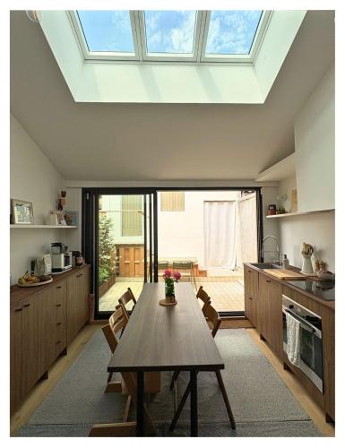 une cuisine avec une table et une grande lucarne dans l'établissement Chouk House - Idéal Famille avec Terrasse, à Bordeaux