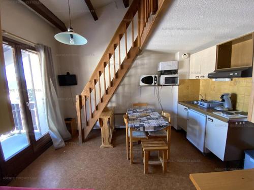 une cuisine avec une table et un évier, ainsi qu'un escalier. dans l'établissement Charmant studio cabine mezzanine pour 4 personnes, proche centre, casier à skis - FR-1-295-130, aux Angles