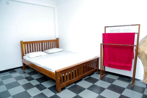 Un pequeño dormitorio con una cama con una manta roja. en White House Resort, en Balangoda