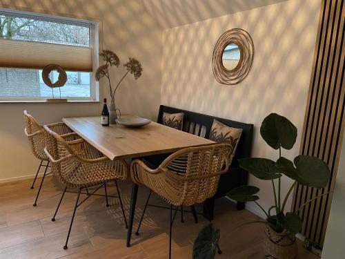 a dining room table with wicker chairs and a mirror at Private Tiny House in Bussum near Amsterdam! in Bussum