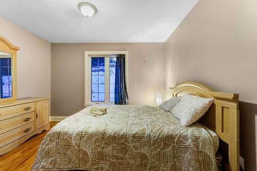 a bedroom with a bed and a dresser and a window at Cozy Chalet Val Morin in Val-Morin