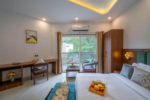 a bedroom with a desk and a bed with a bowl of fruit at Perfectstayz Premium Mystic falls with Rooftop Pool & Cafe in Narendranagar